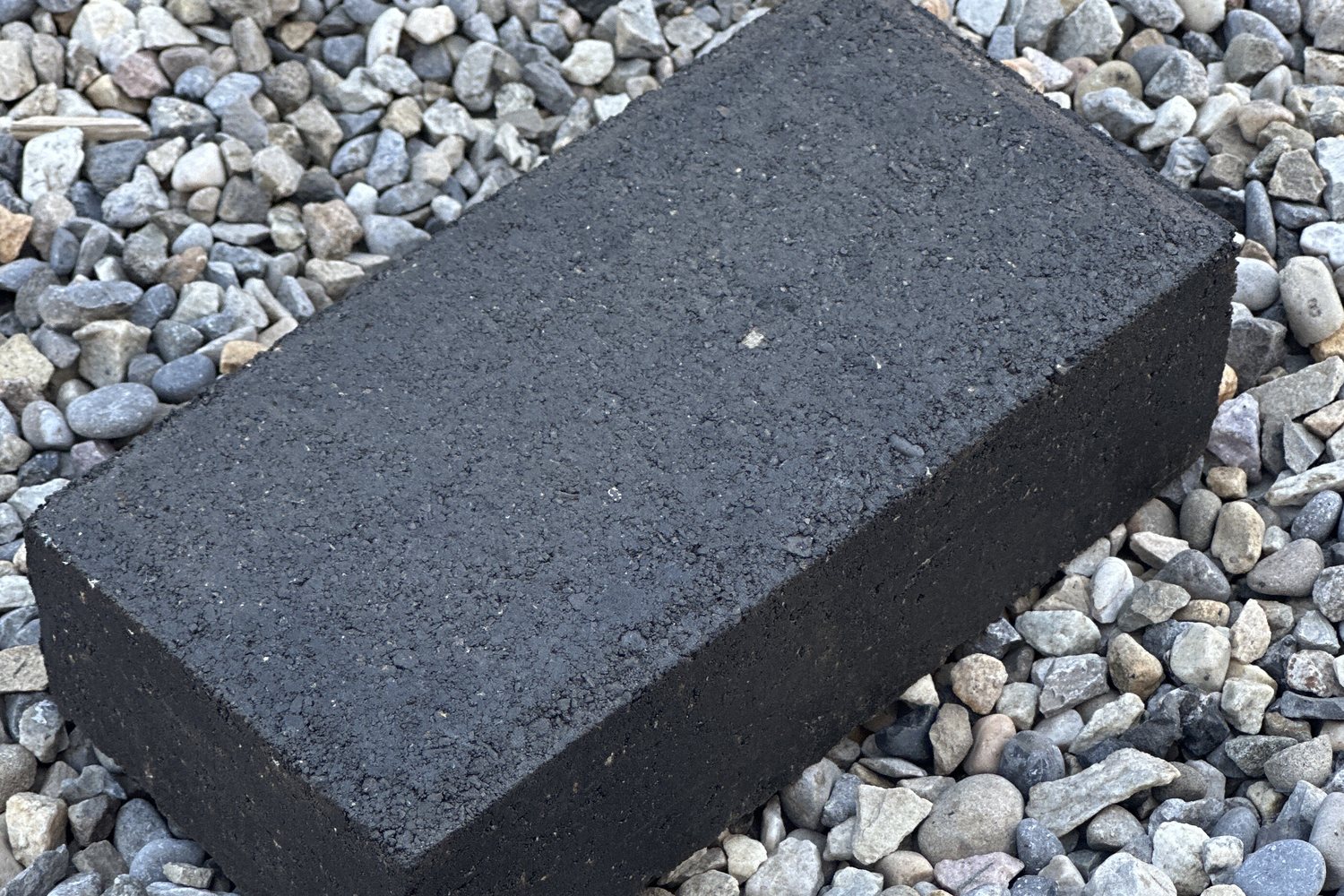 A BlackTop Enduro recycled-asphalt paving block resting on driveway gravel